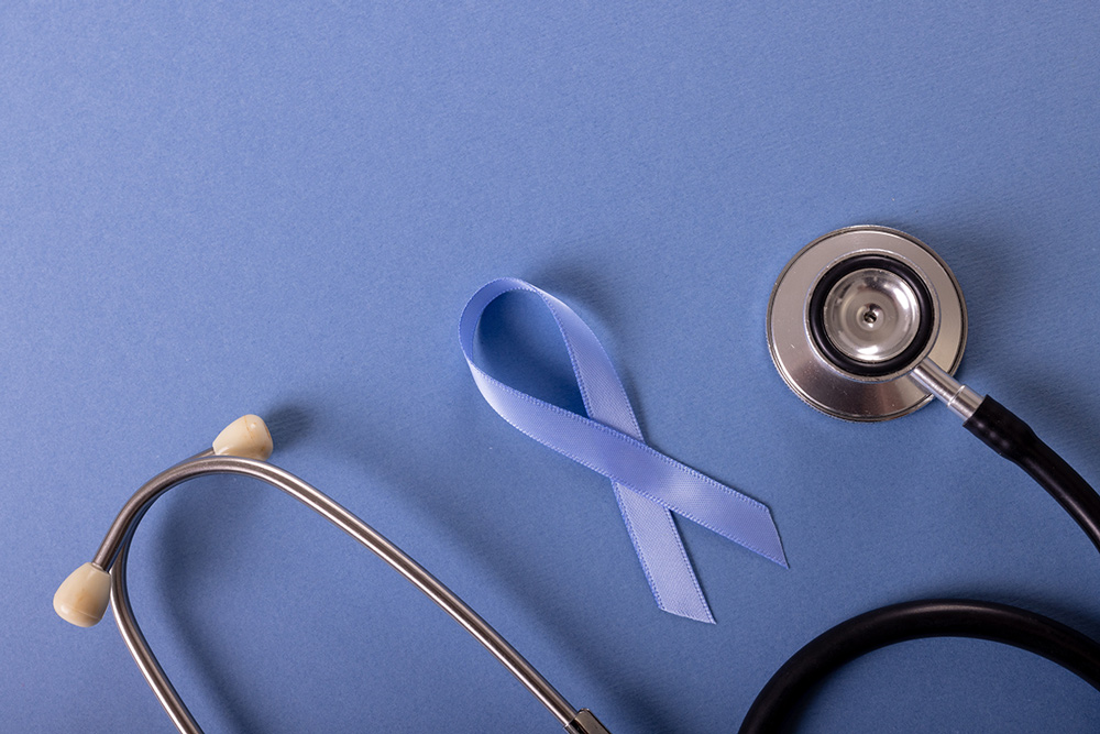 A light blue ribbon and a stethoscope lay on a blue surface